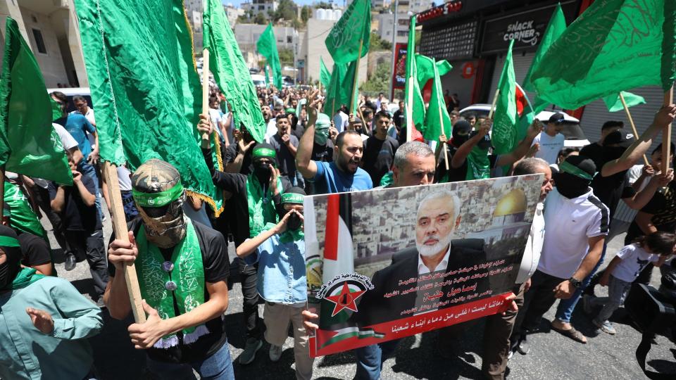  Palestinians waving flags and holding banners march during a demonstration over the assassination of Hamas Political Bureau Chief Ismael Haniyeh in Tehran on July 31, 2024, in Hebron, West Bank. 