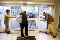 From left: Hilton employees Louie Fonseca, Frankie Monica, Bryan Kinbacher and Jaime Miranda use rope to secure the front door at the Hilton Garden Inn in Fort Myers, Fla. Hurricane Ian has made landfall in southwestern Florida as a massive Category 4 storm. (Douglas R. Clifford/Tampa Bay Times via AP)