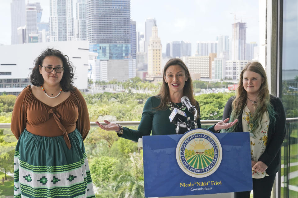Florida Commissioner of Agriculture and Consumer Services Nikki Fried, center, speaks during a news conference along with youth climate leaders, Valholly Frank, left, and Delaney Reynolds, right, Thursday, April 21, 2022, at the Phillip & Patricia Frost Museum of Science in Miami. Fried unveil a proposed rule to require that utilities operating in the state generate 100% of their electricity from renewable sources of energy by 2050. (AP Photo/Wilfredo Lee)