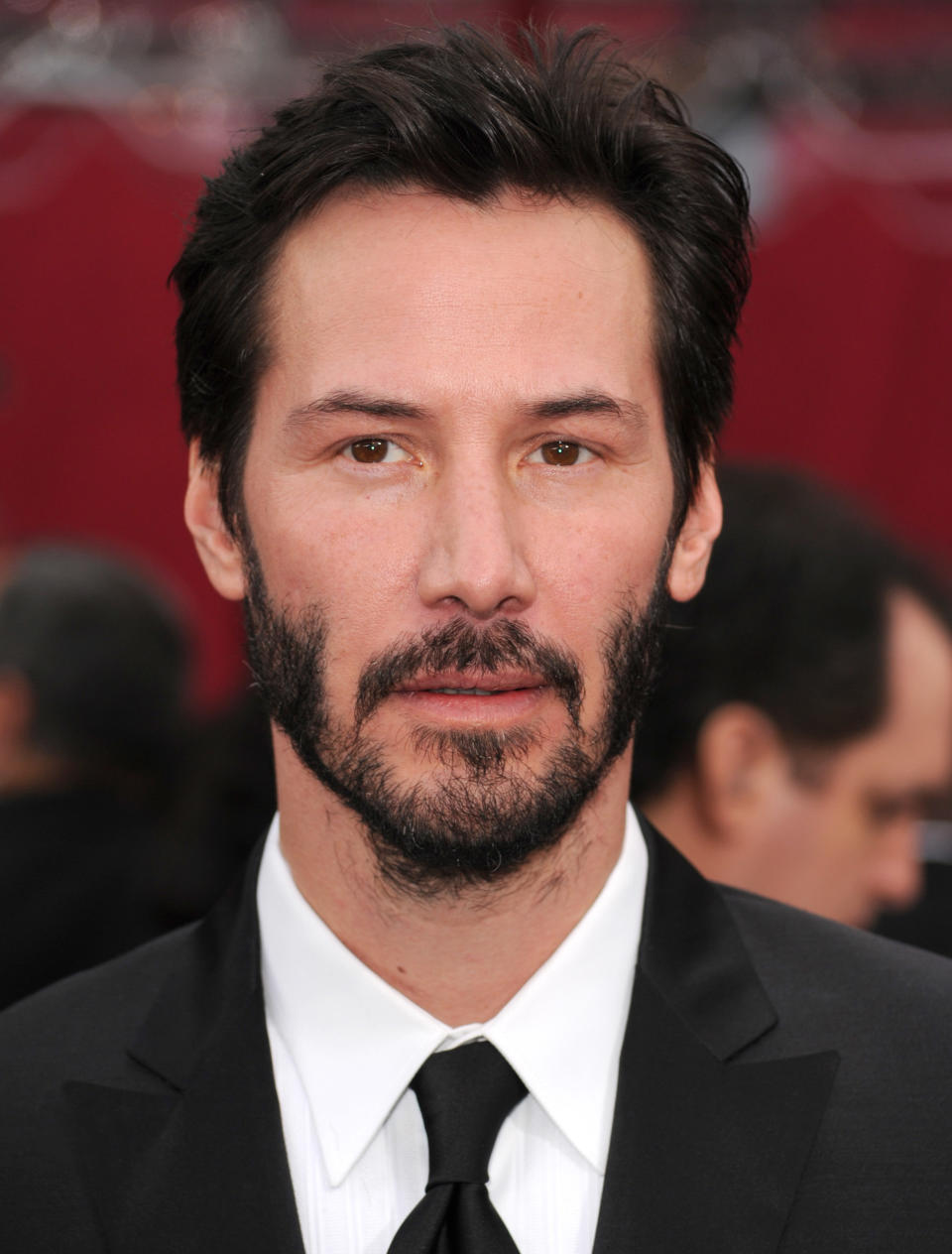 Man in a black suit and tie on a red carpet