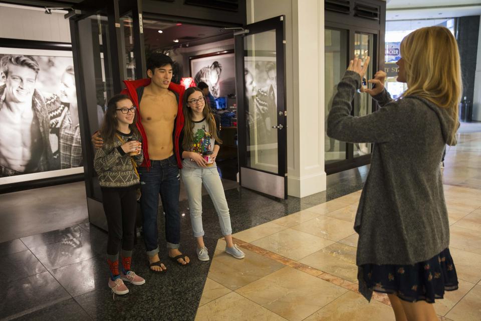 Two teenagers take a photograph with an Abercrombie & Fitch employee inside Westfield San Francisco Centre during Black Friday in San Francisco, California November 29, 2013. Black Friday, the day following the Thanksgiving Day holiday, has traditionally been the busiest shopping day in the United States. REUTERS/Stephen Lam (UNITED STATES - Tags: BUSINESS)