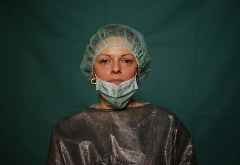 Laura Orsini, 39, an administrative worker at Rome's COVID 3 Spoke Casalpalocco Clinic poses for a portrait, Friday, March 27, 2020, during a break in her daily shift. The intensive care doctors and nurses on the front lines of the coronavirus pandemic in Italy are almost unrecognizable behind their masks, scrubs, gloves and hairnets. (AP Photo/Domenico Stinellis