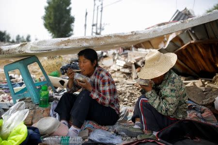 Migrant workers Wang Qin (L) and her sister Wang Jun eat lunch during a break from collecting scrap materials from the debris of demolished buildings at the outskirts of Beijing, China October 1, 2017. Picture taken October 1, 2017. REUTERS/Thomas Peter