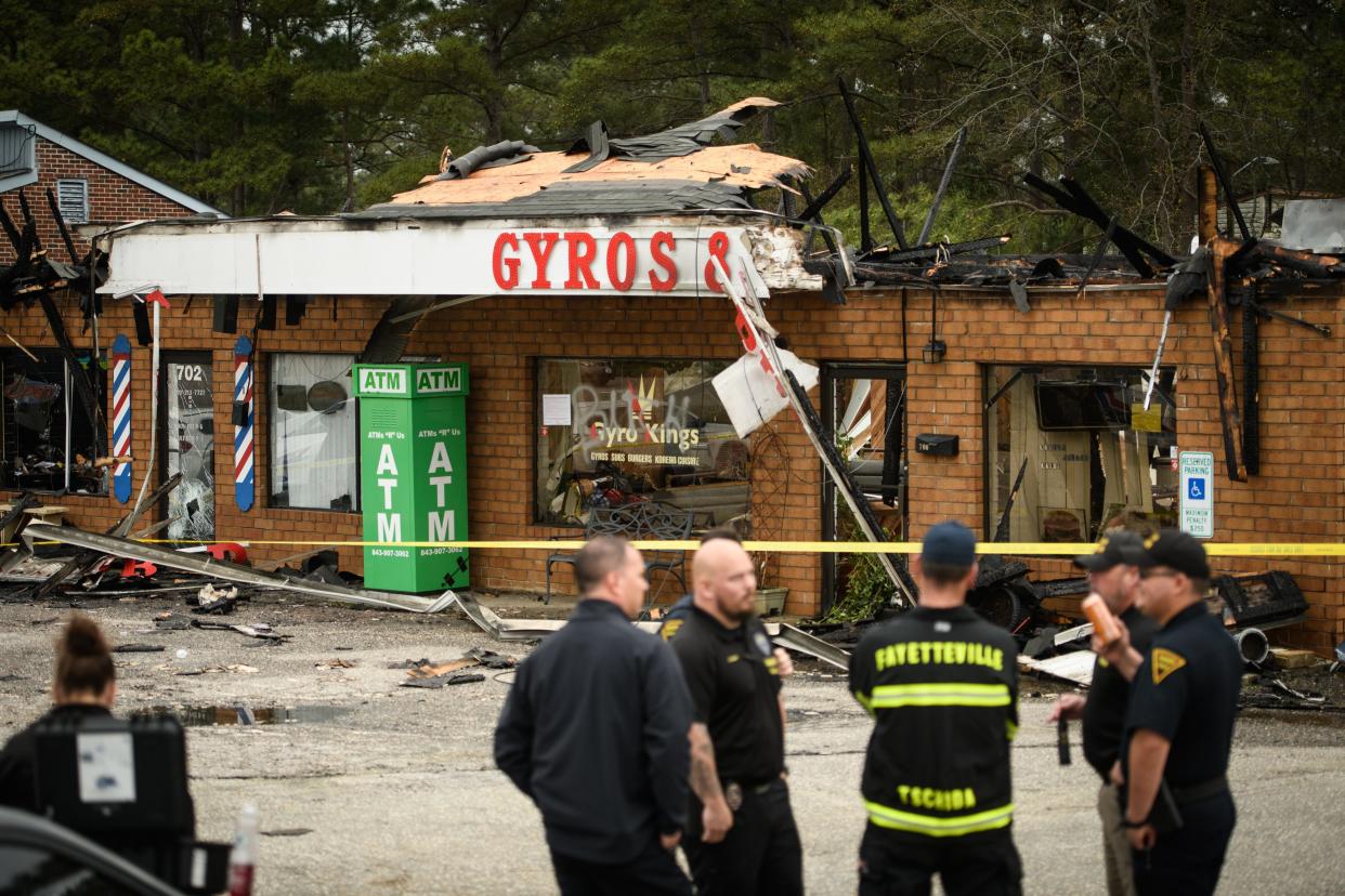 Firefighters and police officers stand outside Gyro Kings restaurant and ACC Sports Cuts barbershop on the 700 block of N. Reilly Road which were destroyed in a fire on Wednesday, March 23, 2022.