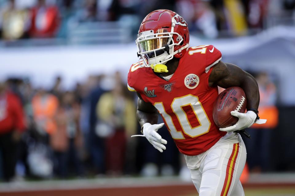 Tyreek Hill runs with the ball in his arm during a game.