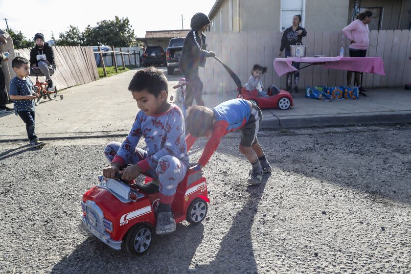 Pajaro, CA, Thursday, March 16, 2023 - Residents of Brooklyn St. offer food to neighbors as their children frolic on a road that was submerged by floodwaters nearly a week ago. Most Pajaro residents remain evacuated as those remaining deal with the aftermath of flooding caused by a damaged levee during last week's massive rainstorm. (Robert Gauthier/Los Angeles Times)