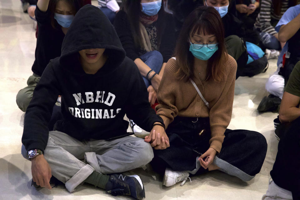 Protestors gather during a sit-in at a shopping mall to commemorate the four-month anniversary of an assault on commuters and protesters by armed men at a nearby train station in Hong Kong, Thursday, Nov. 21, 2019. A small but determined group of protesters remained holed up Thursday inside a Hong Kong university campus as the city's largest pro-Beijing political party urged voters to "kick out the black force" in upcoming elections seen as a key gauge of public support for anti-government protests. (AP Photo/Ng Han Guan)