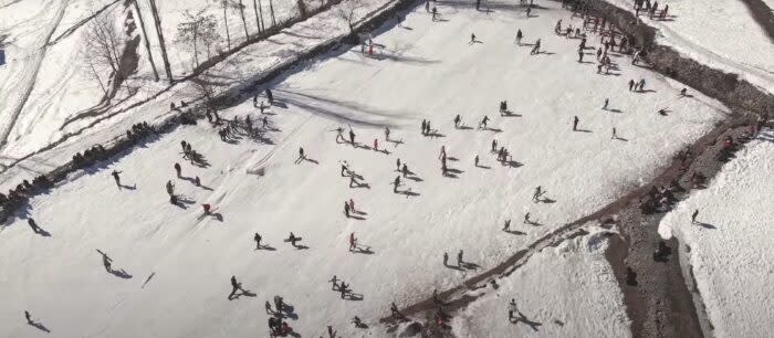 a wide, birds eye view shot of children skiing and snowboarding 