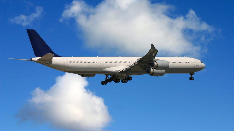 a white airliner with landing gear deployed