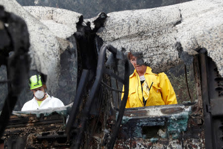 Larry and Karen Atkinson, of Marin, search for human remains in a van destroyed by the Camp Fire in Paradise, California, U.S., November 14, 2018. REUTERS/Terray Sylvester