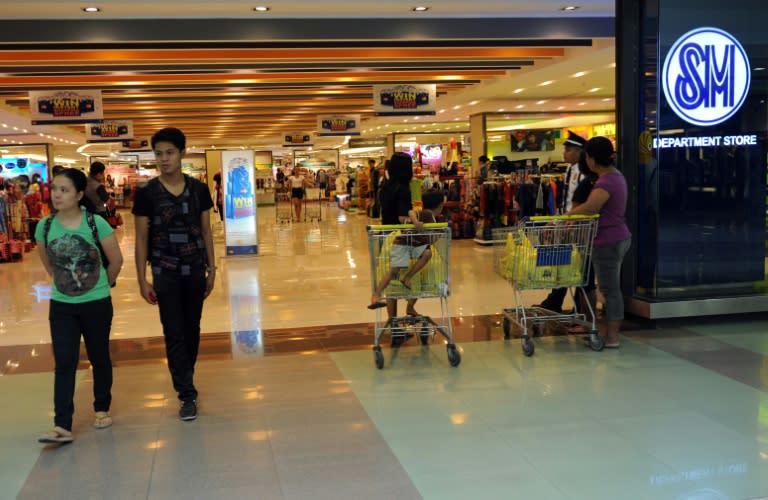 Shoppers walk past a logo of Philippine's largest shopping mall operator ShoeMart (SM) in one of their stores in Manila