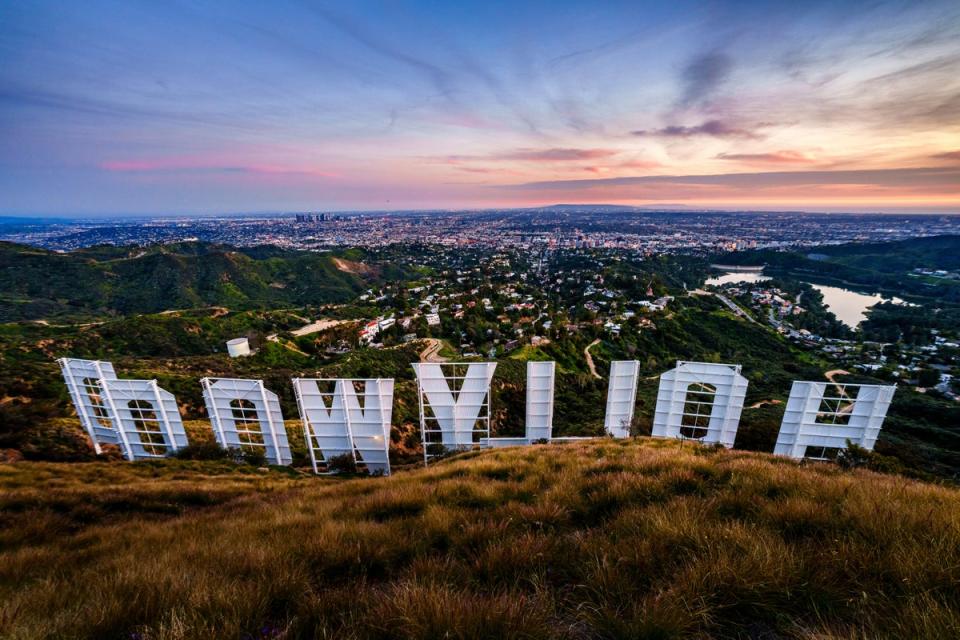 Sunset casts a pink glow over the Los Angeles skyline as seen from behind the famous Hollywood sign Wednesday evening, March 8, 2023 (AP)