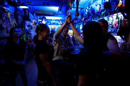 American James John Goodman, 51, does a high-five with female servers inside a bar in Subic, north of Manila, Philippines November 10, 2017. REUTERS/Romeo Ranoco