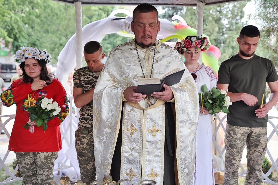 Soldiers Vitalii Orlich and his bride Kristina (R) and Volodymyr Mykhailuk and his bride Hrystyna are married during joint wedding ceremony on June 12, 2022 in Druzhkivka, Donetsk Oblast, Ukraine. All four are soldiers in the Ukrainian army serving with the 14th separate mechanized brigade in eastern Ukraine. Both couples met while serving in the army after the start of the war with Russia. Ukrainian forces are engaged in a back-and-forth battle with Russia for key towns along the western edge of the Donetsk and Luhansk regions, where Moscow is focusing its firepower.