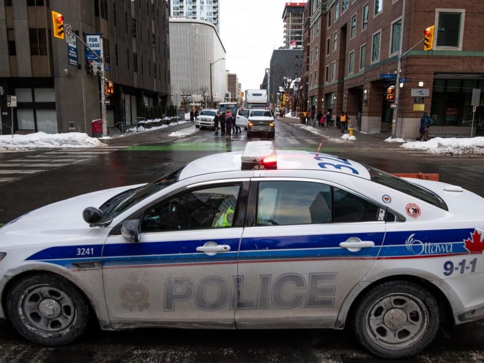 An Ottawa police cruiser sits at Laurier Avenue W. and Metcalfe Street during last winter's convoy protest. According to the final report of the Public Order Emergency Commission, Ottawa police failed to act upon intelligence that was available before the convoys descended on the capital. (Justin Tang/The Canadian Press - image credit)