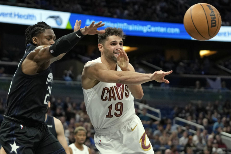 Cleveland Cavaliers' Raul Neto (19) passes the ball as his path to the basket is blocked by Orlando Magic's Admiral Schofield, left, during the first half of an NBA basketball game, Thursday, April 6, 2023, in Orlando, Fla. (AP Photo/John Raoux)