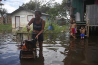 Edileuza Pereira da Silva cooks for her family outside her home, flooded by the rise of the Negro river in Iranduba, Amazonas state, Brazil, Monday, May 23, 2022. The Amazon region is being hit hard by flooding with 35 municipalities that are facing one of their worst floods in years and the water level is expected to rise over the coming months. (AP Photo/Edmar Barros)