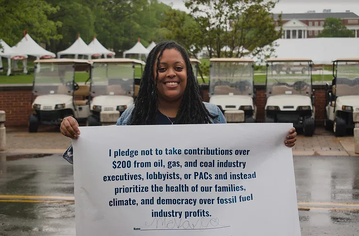 Mckayla Wilkes, 28, holds a sign bearing her signature on the No Fossil Fuel Money pledge.&nbsp; (Photo: Mckayla Wilkes)