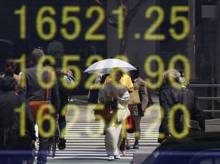 A woman clad in a kimono is reflected in an electronic board displaying Japan's Nikkei share average outside a brokerage in Tokyo, Japan, April 18, 2016. REUTERS/Toru Hanai