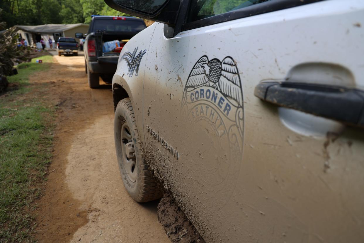 A coroner's vehicle is parked along Bowling Creek in Breathitt County, Kentucky. The county has seen six flood-related deaths so far.
