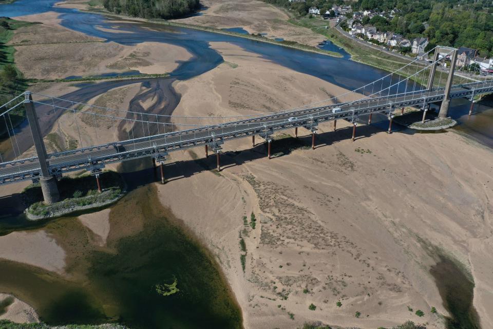 This aerial picture shows a bridge over the dried out Loire River bed at Loireauxence, western France on September 20, 2022. - This summer was France's second-hottest on record with average temperatures 2.3C above the norm, a slew of large-scale wildfires which ravaged much of the southwest and widespread drought as well as several severe storms. (Photo by Damien MEYER / AFP)