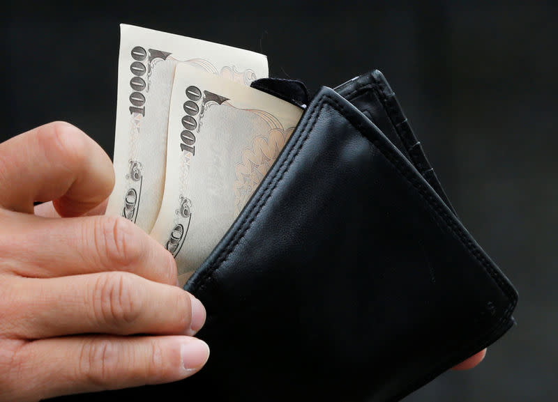 A man holds Japanese 10,000 Yen ($121) bank notes in front of a bank in Tokyo November 22, 2012. REUTERS/Kim Kyung-Hoon/File Photo