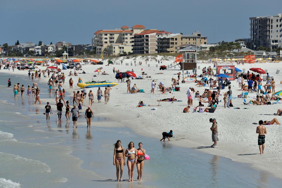 Visitors enjoy Clearwater Beach, Wednesday, March 18, 2020, in Clearwater Beach, Fla. Beach goers are keeping a safe distance from each other to help protect from the spread of the  new coronavirus.