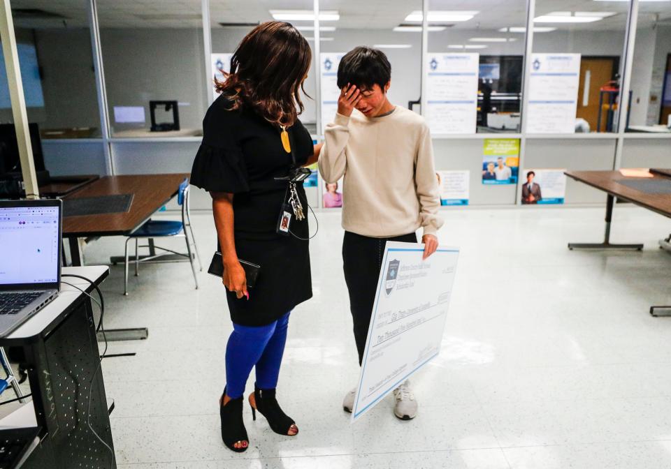 Toetta Taul, principal at Iroquois High School, congratulates senior Gia Tran after he received a $10,500 scholarship check to UofL from JCPS Friday morning. Tran wants to study electrical engineering in college. May 19, 2023.