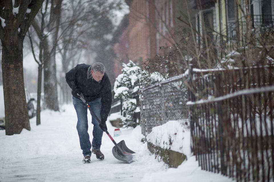 New York City Mayor Bill de Blasio clears the sidewalk of snow in front of his Brooklyn home in New York