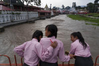 Girls look at the Bagmati River, swelled by monsoon rains, in Kathmandu, Nepal, Wednesday, July 27, 2022. A governmental committee set up to help clean the river is working on upstream dams where rainwater can be captured and stored during the monsoon season and released during the dry months to flush the river, moving waste downstream from Kathmandu. (AP Photo/Niranjan Shrestha)