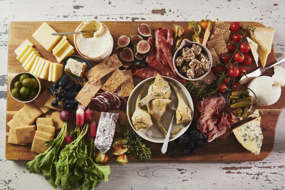 A variety of cheeses, spreads and cured meats are displayed on a graze board. Olives, pickles, and marinated vegetables of all kinds offer a tangy crunch and briney flavor in between bites of cheeses and charcuterie. (Katie Workman via AP)