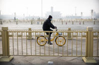 In this Monday, Jan. 27, 2020 photo, a man wearing a face mask rides a bicycle past Tiananmen Square, normally crowded with tourists during the Lunar New Year holiday, in Beijing. Fears of a virus outbreak have kept many indoors and at home in China's capital. Cultural landmarks such as the Great Wall and Forbidden City have closed their doors to visitors, nearly deserted shopping malls have reduced their operating hours, and restaurants that remain open draw just a handful of customers. (AP Photo/Mark Schiefelbein)