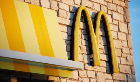 The side of a McDonald's restaurant, closeup on the company's golden arch logo.