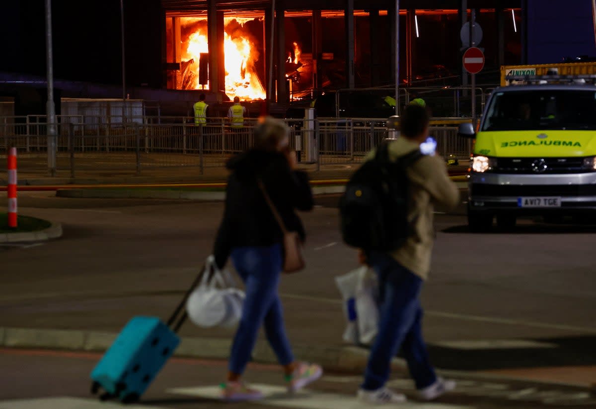 People leave as emergency services respond to a fire in Terminal Car Park 2 at Luton Airport (REUTERS)