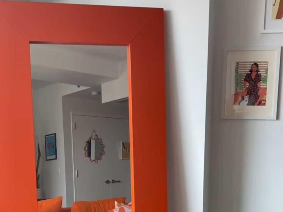A large, floor-length mirror with an orange frame