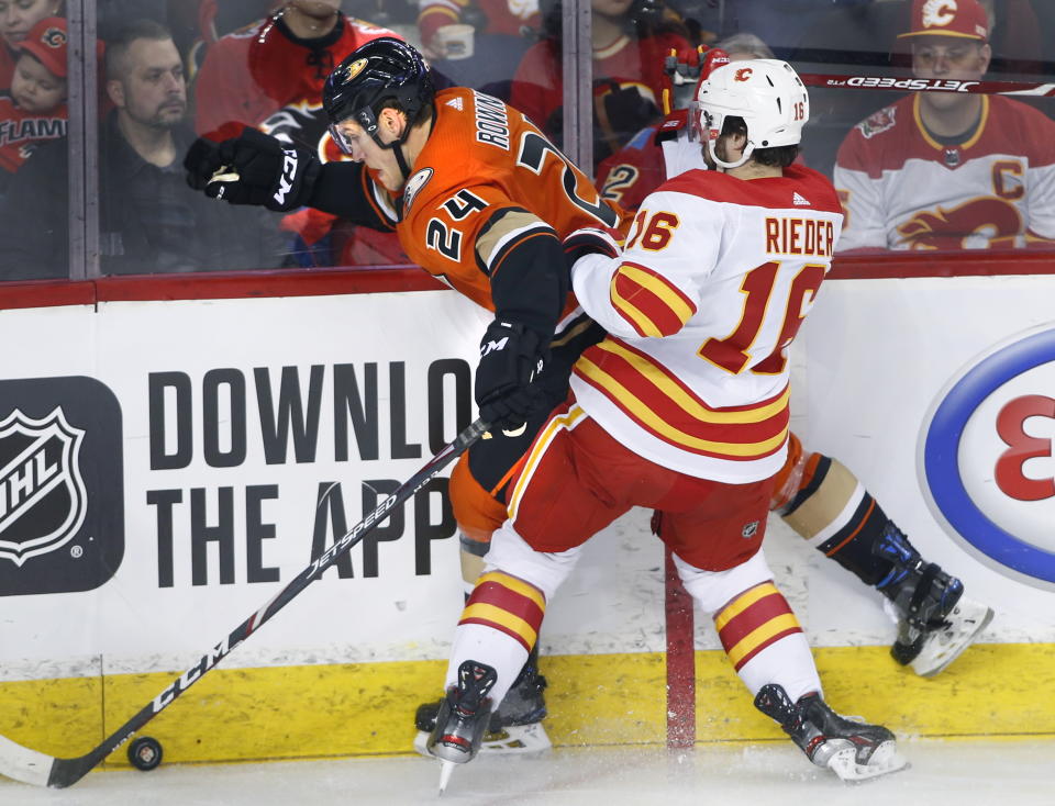 Anaheim Ducks' Carter Rowney, left, takes a hit from Calgary Flames' Tobias Rieder, from Germany, during second period NHL hockey action in Calgary, Alberta, Monday, Feb. 17, 2020. (Larry MacDougal/The Canadian Press via AP)