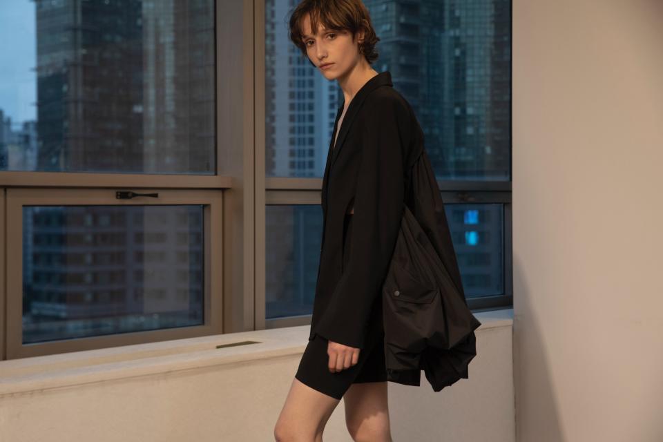 A look from bespoke brand BESFXX's SS 2023 collection features a person wearing a black short blazer with a balloon skirt detail at the back.