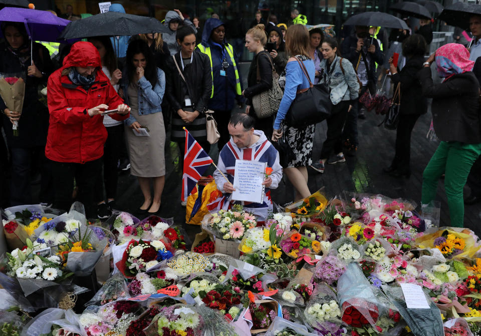 People look at floral tributes after a vigil to remember the victims