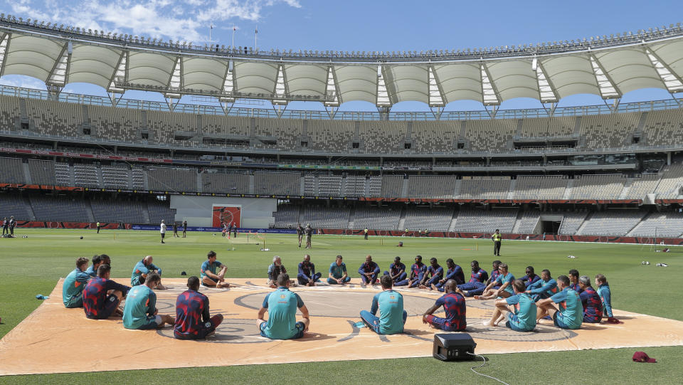 Australian and West Indies players participate in a "barefoot circle" ceremony ahead of play on the first day of the first cricket in Perth, Australia, Wednesday, Nov. 30, 2022. The barefoot circle is a cricket centric way for players and teams to take a moment prior to matches to acknowledge the traditional owners of the land, connect to each other as opponents and pay respect to the country. (AP Photo/Gary Day)