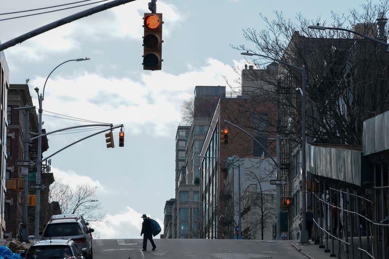 A man wearing a protective mask crosses Lexington Avenue in Spanish Harlem during the outbreak of the coronavirus disease (COVID-19) in New York