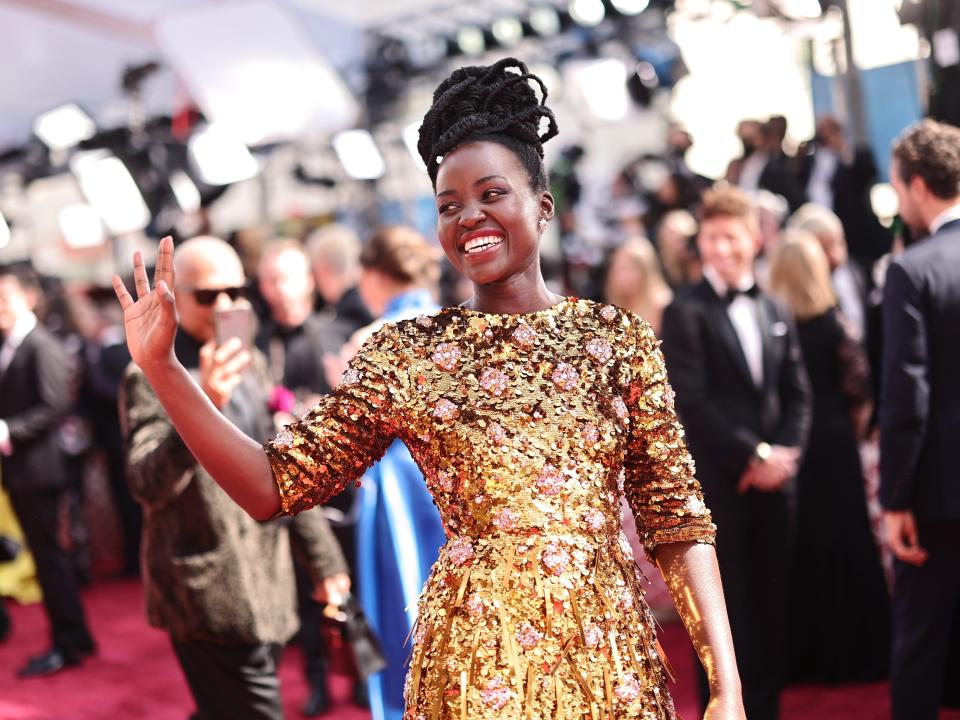 Lupita Nyong'o in gold dress with crowd in background on Oscars red carpet