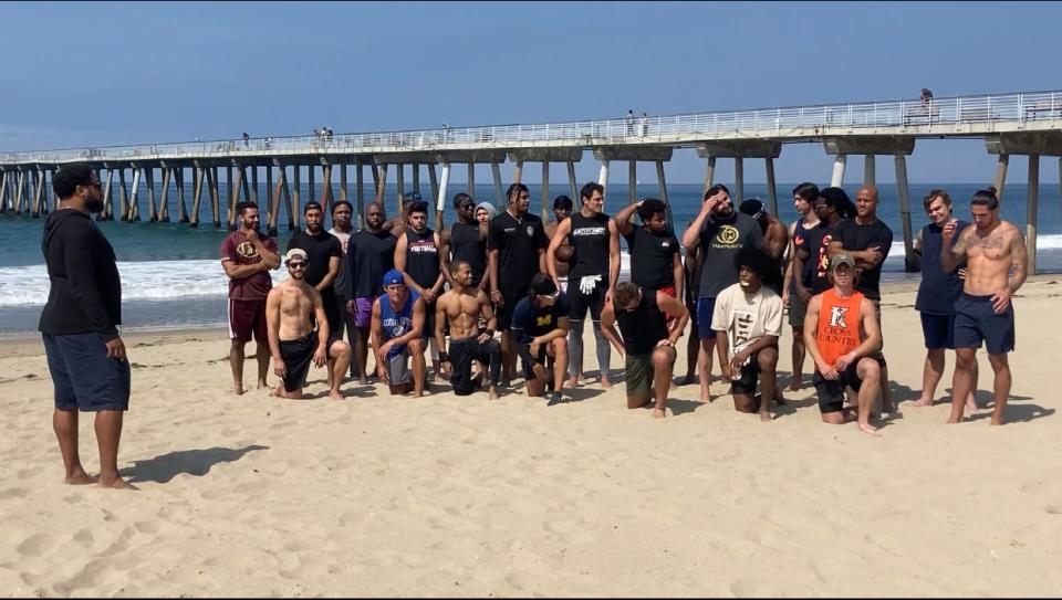 Tully Banta-Cain (left) addresses Beach Football players in a preliminary sand tackle game in Hermosa Beach, California.