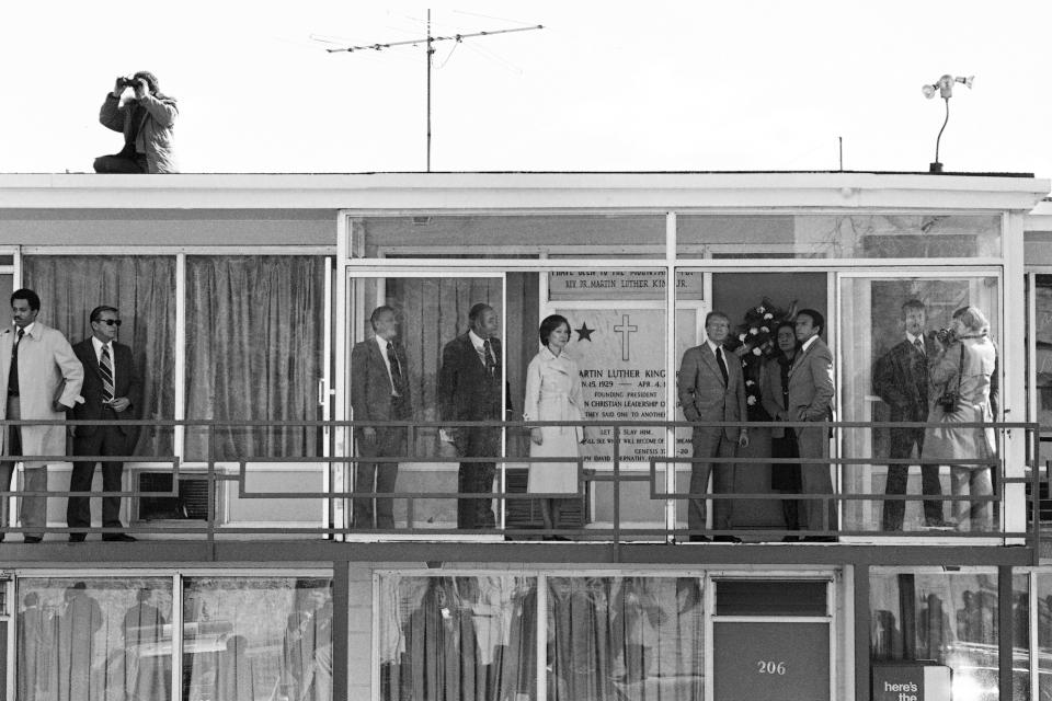 FILE - President Jimmy Carter and first lady Rosalynn Carter, along with Coretta Scott King and United Nations Ambassador Andrew Young, right, center, stand on the balcony of the hotel in Memphis, Dec. 9, 1978 where Martin Luther King Jr. was assassinated. Carter stopped at the site and placed a wreath on the door while en route to the airport for a flight to Washington. On the roof at upper left, a security agent keeps a lookout with binoculars. (AP Photo/File)