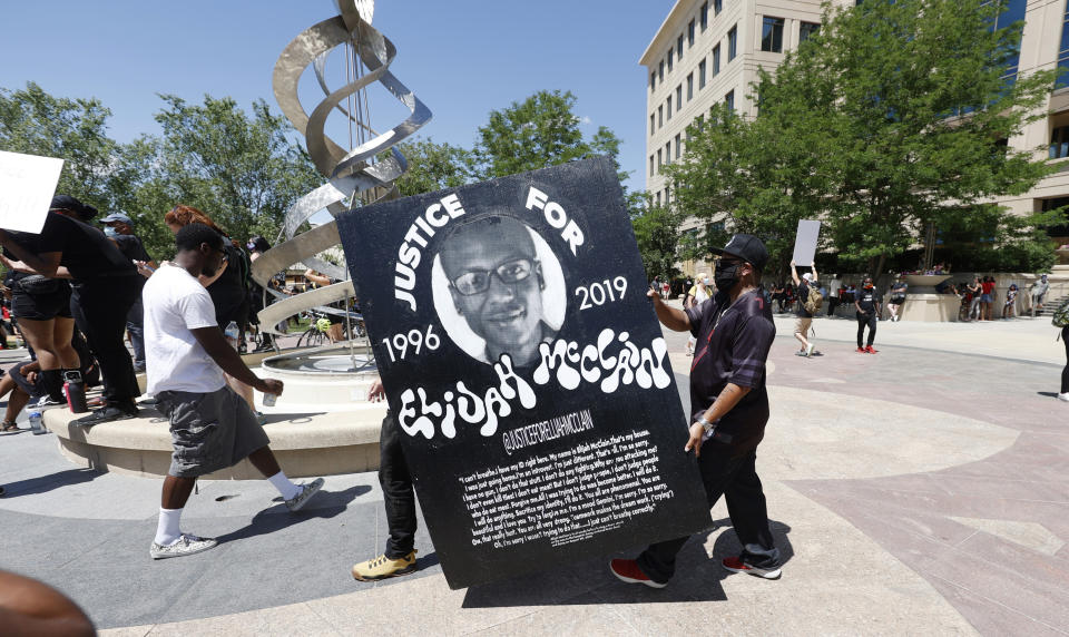 FILE - Demonstrators carry a giant placard during a rally and march over the death of 23-year-old Elijah McClain outside the police department in Aurora, Colo., June 27, 2020. A Colorado prosecutor says two paramedics failed to properly care for McClain when they overdosed the Black man with a sedative that he didn’t need. McClain died after being stopped and forcibly restrained by police officers and then injected with ketamine in 2019 in the Denver suburb of Aurora. (AP Photo/David Zalubowski, File)
