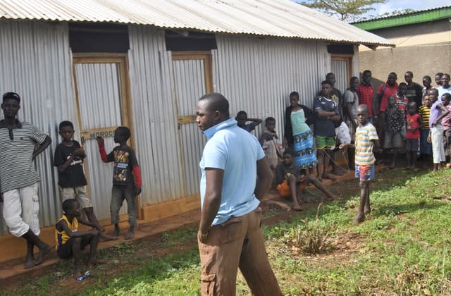 Villagers gather outside a small house where they claimed the suspected kidnappers of an Italian woman had been staying in recently, in the village of Chakama