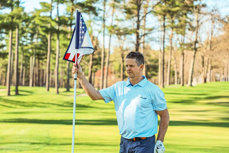 Kevin Fowler holds the pin while wearing a Pure Golf Apparel shirt at Wedgewood Pines Country Club in Stow this past April. Fowler's sons, Ian and Will, started the golf clothing company.