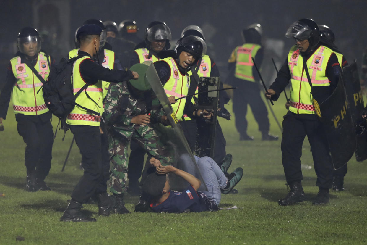 Security officers detain a fan during a clash between supporters of two Indonesian soccer teams at Kanjuruhan Stadium in Malang, East Java, Indonesia, Saturday, Oct. 1, 2022. Clashes between supporters of two Indonesian soccer teams in East Java province killed over 100 fans and a number of police officers, mostly trampled to death, police said Sunday. (AP Photo/Yudha Prabowo)