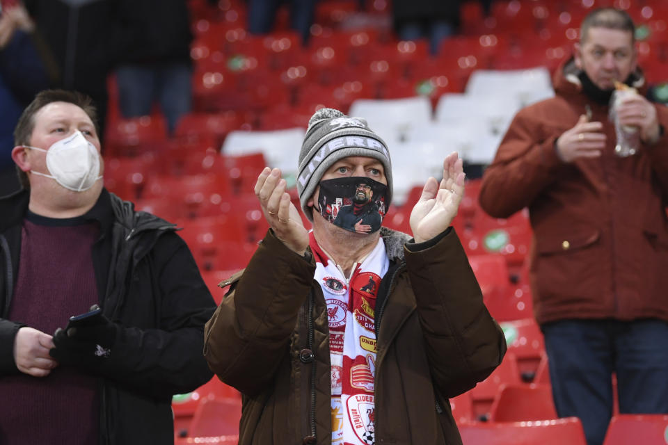 A Liverpool fans with a Jurgen Klopp protective face mask applauds before the start of an English Premier League soccer match between Liverpool and West Bromwich Albion at the Anfield stadium in Liverpool, England, Sunday Dec. 27, 2020. (Stu Forster/Pool via AP)