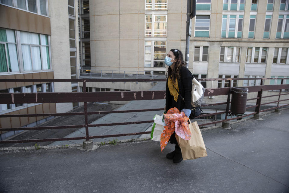 In this photo taken on Friday, April 10, 2020 nurse Cristina Settembrese arrives at the entrance of the San Paolo hospital for her work shift carrying food for colleagues in Milan, Italy. (AP Photo/Luca Bruno)