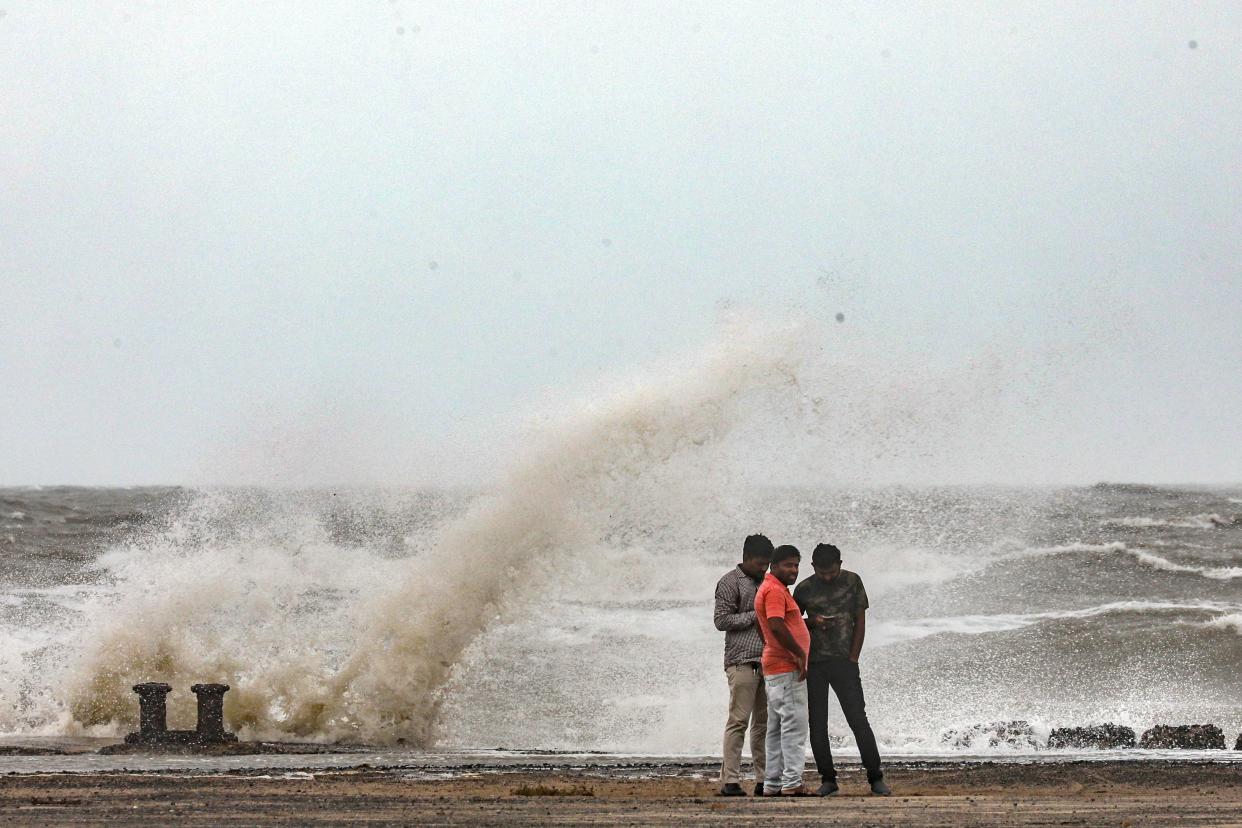 People stand near the coast during high tide in Mandvi, in the Kutch district of the western state of Gujarat, India (EPA)